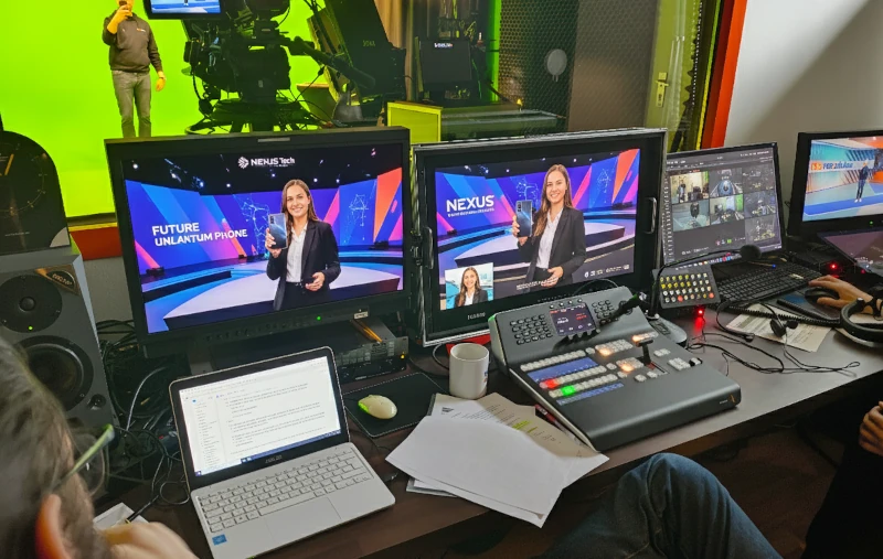 Live Streaming Agentur 20 Videoregie einer Live-Produktion für Marketing-Event/Pressekonferenz in einem virtuellen Studio. Regieteam im Anschnitt, Redner auf großer Leinwand, Kameraleute an Kameras.